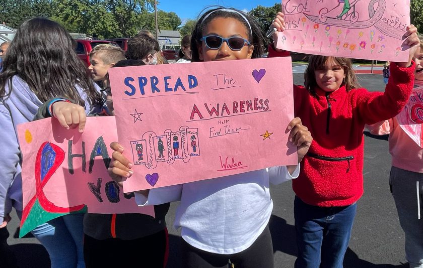 students standing outside holding a signs to find missing children