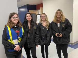 four students wearing black jackets with the scales of justice on it are standing in a hallway