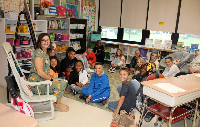 students sitting on floor and teacher on chair