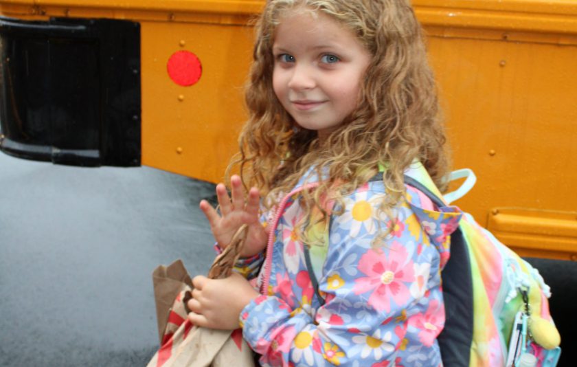 student with long curly hair outside bus
