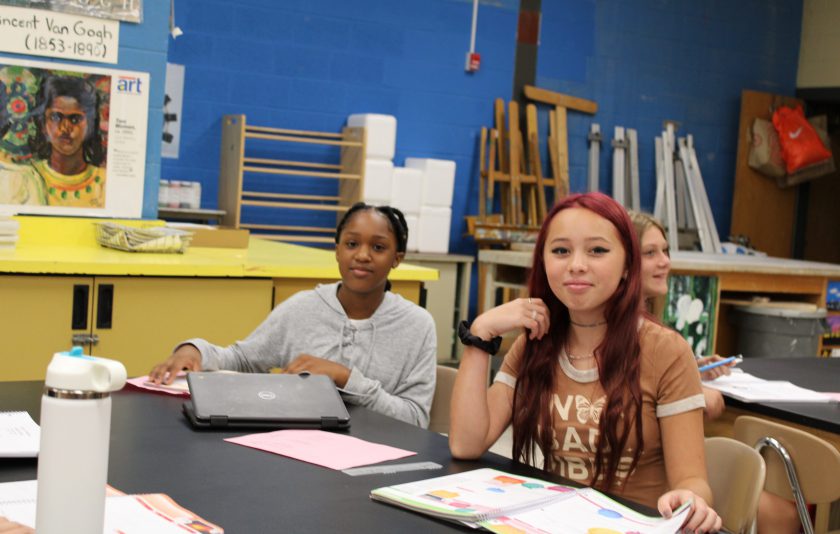 one student with laptop half open and another student with long maroon hair