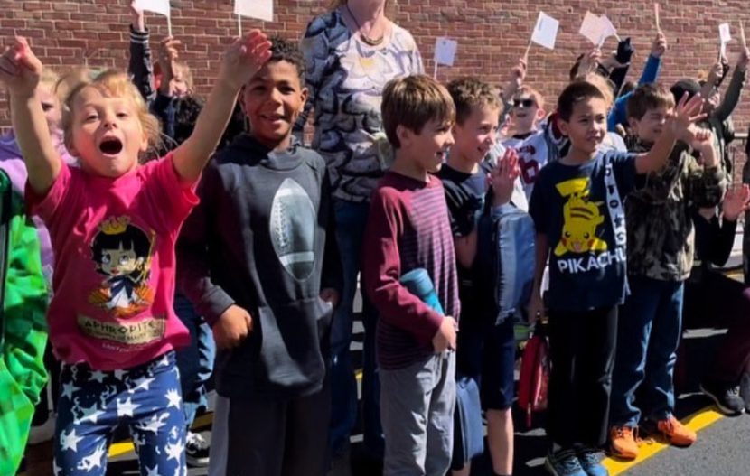 kids jumping up and down outside their school