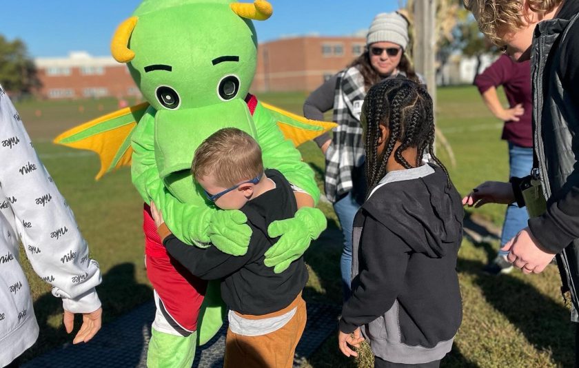 little student hugs dragon mascot