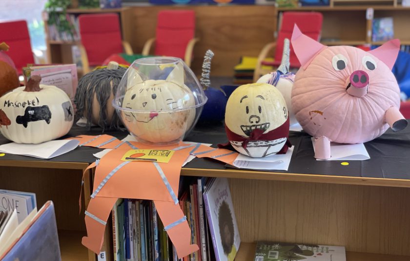 pumpkins decorated like book characters displayed on library bookshelf