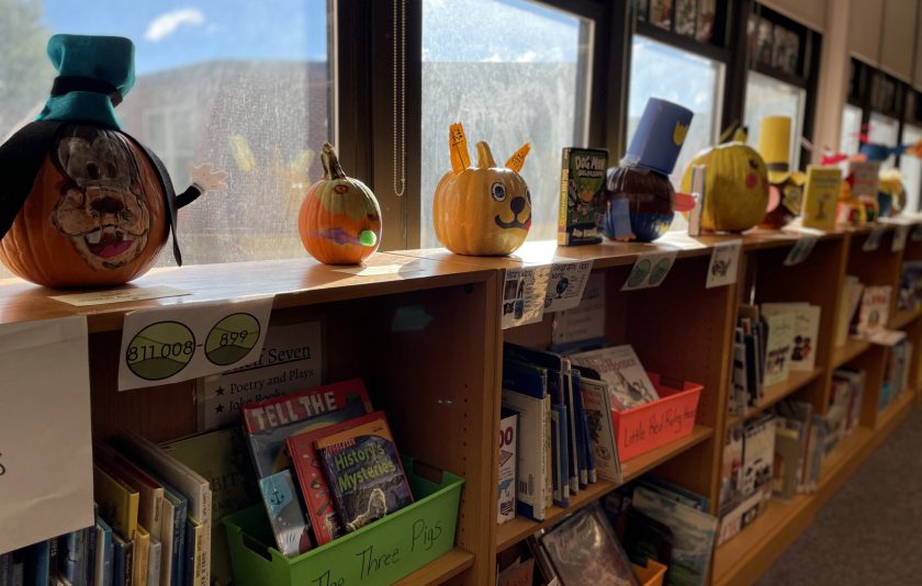 pumpkins casting shadows in front of a lit window