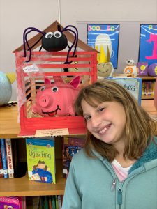 smiling student next to a pig made out of a pumpkin in a pig pen and a black spider on top