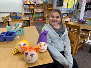 student sits next to three pumpkins representing the hocus pocus sisters