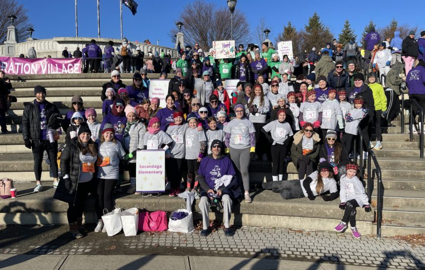 a huge group of runners holding signs standing outside
