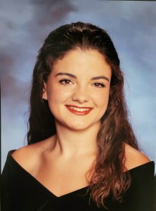 senior photo with traditional black drape. Student has long dark wavy hair and brown eyes