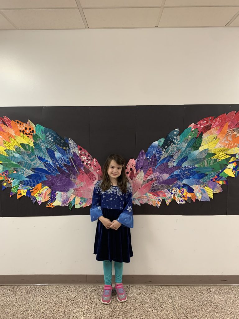 student standing in front of colorful feathers 