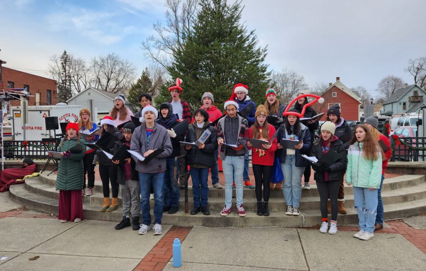 singing carols in front of a holiday tree
