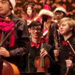student wearing a bowtie and holding a violin in the orchestra