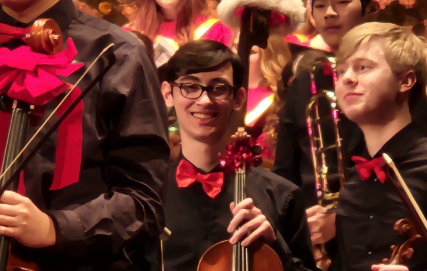student wearing a bowtie and holding a violin in the orchestra