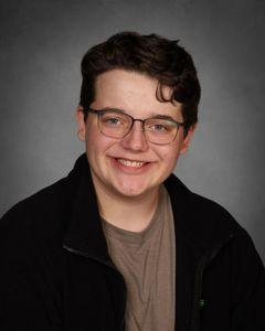 student with thin rimmed glasses wearing a black fleece with a brown shirt under