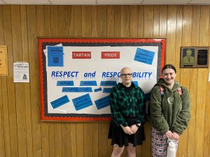 two students stand off to the side of a sign with the words respect and responsibility
