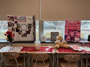 candy and a teddy bear on the table and posters behind that stating that love is not abuse
