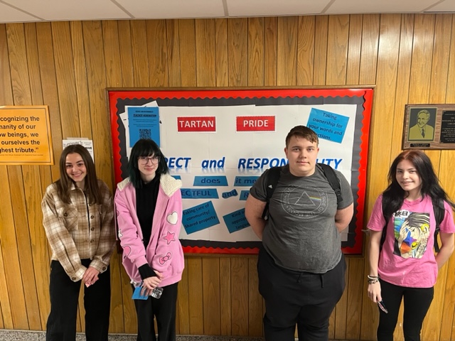 four students standing in front of respect and responsibility sign