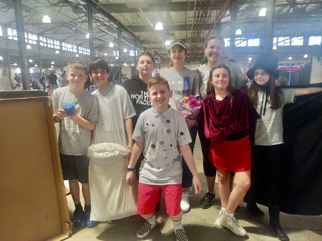 six students and two coaches smiling in a warehouse