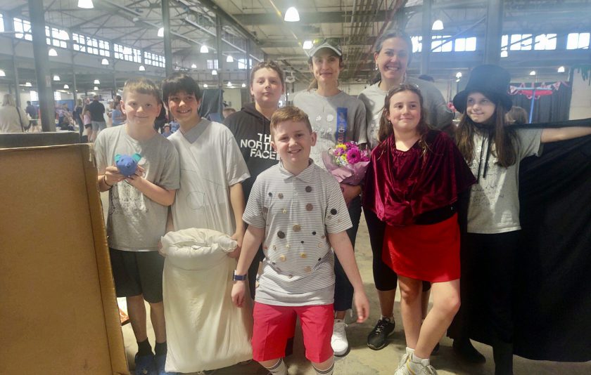 six students and two coaches smiling in a warehouse