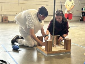 two students building a small structure with wood