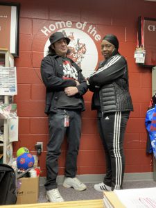 two adults dressed up as RUN DMC, wearing gym clothes standing with their arms crossed 