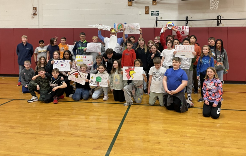 students piled up in a gymnasium holding handmade flags