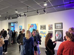 people standing around an art gallery with artwork on the walls around them