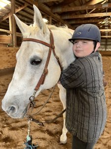 student hugging a white horse's head
