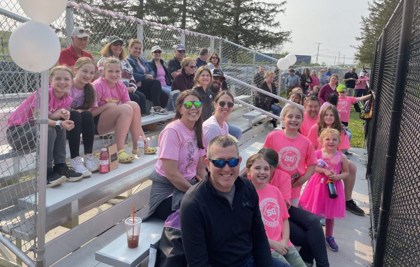 teachers, parents and students on bleachers at softball game
