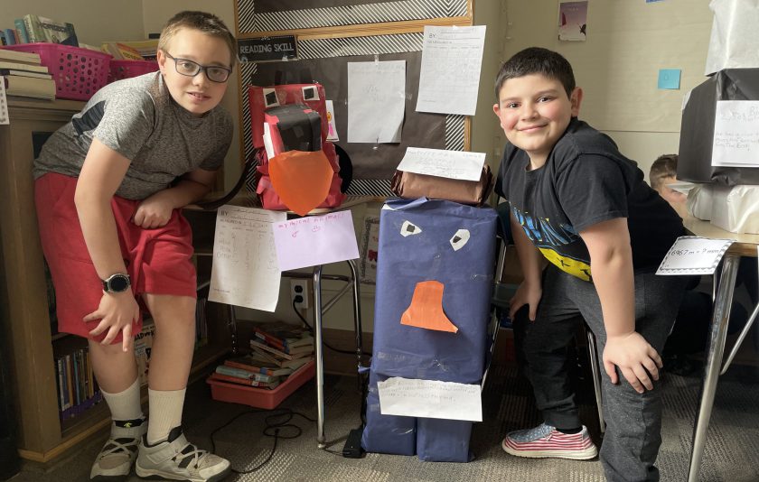 two students crouched over their boxes they made into animals