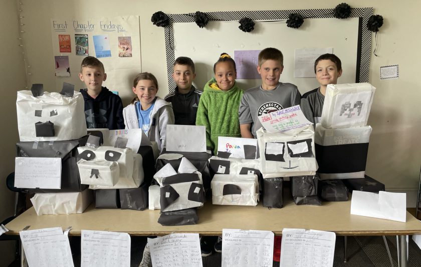 seven students standing behind their boxes they made look like pandas