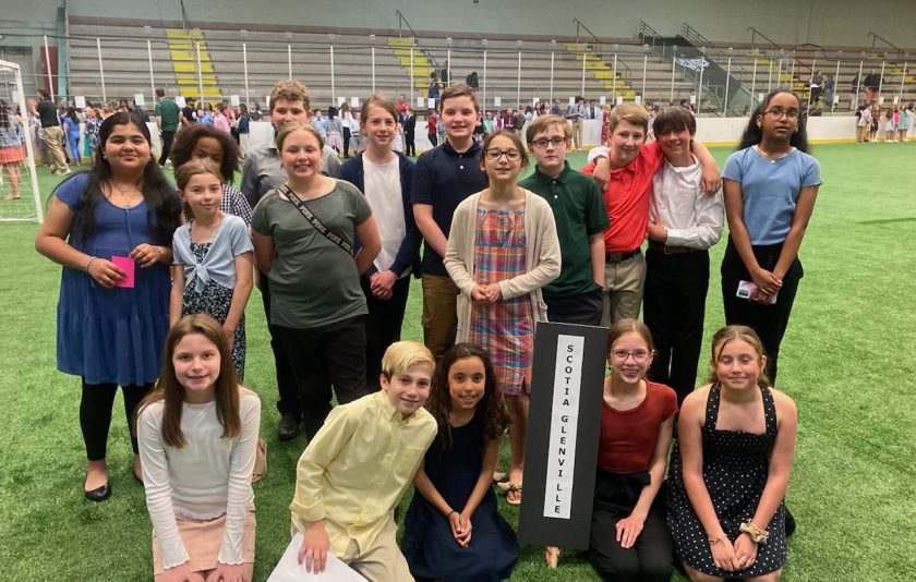Students kneeling and other students stand behind them