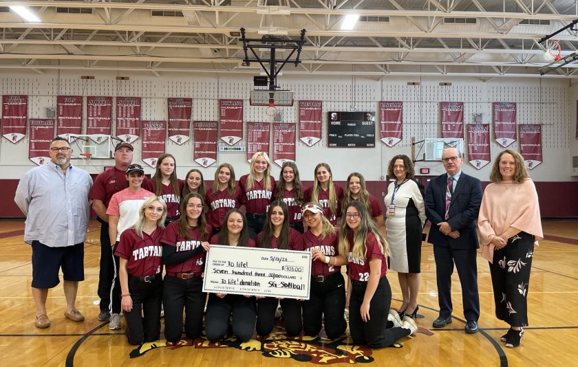 Softball team members display oversized check