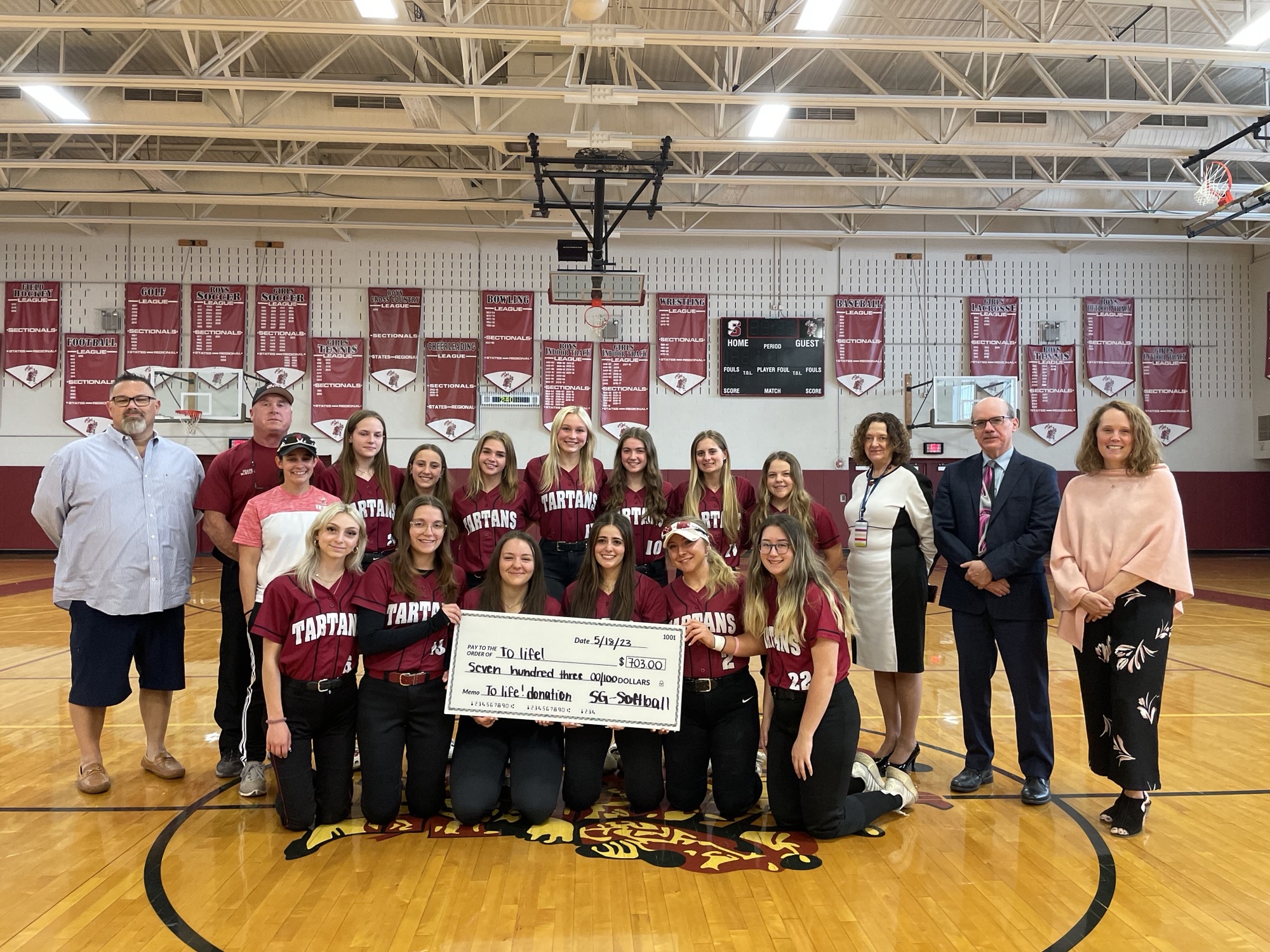 Softball team members display oversized check