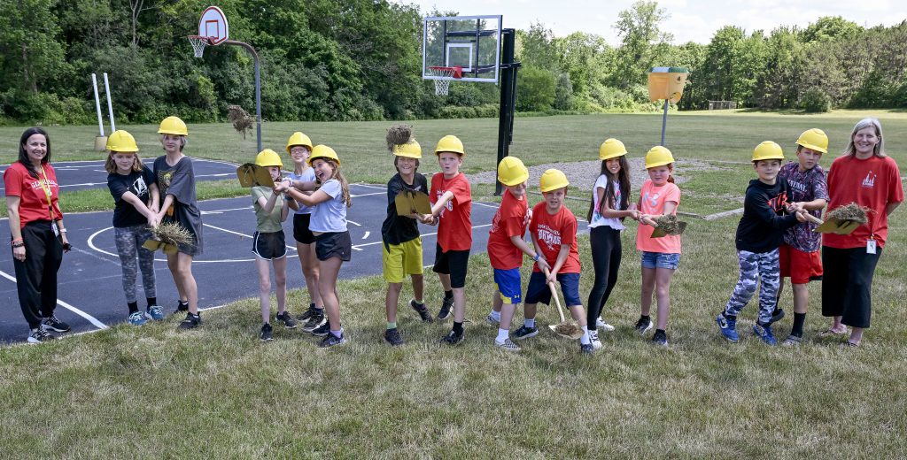 students throw shovels full of dirt into the air