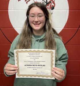 student holding certificate smiles for camera