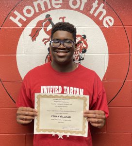 student holding certificate smiles for camera