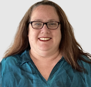 A woman with glasses and long hair and is wearing a blue-green collared shirt