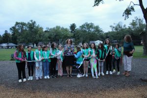 girl scouts and troop leaders cutting a ribbon 