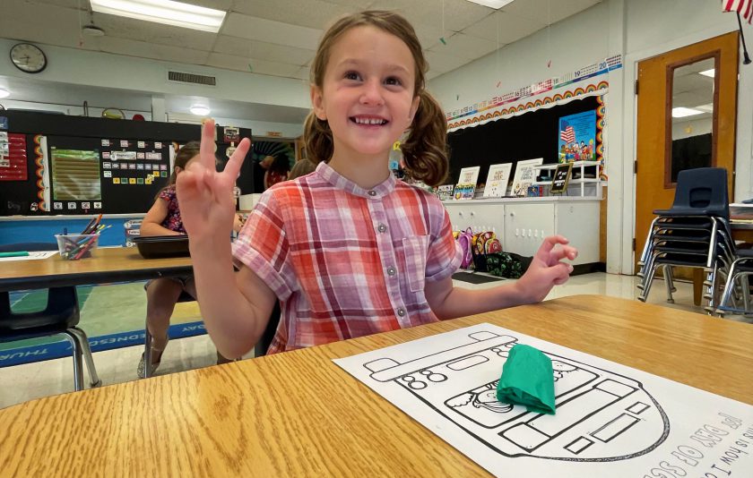 student looks up and gives peace sign