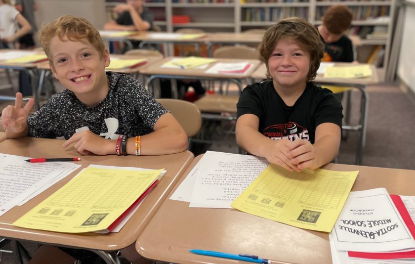 one student smiles and the other flashes a peace sign