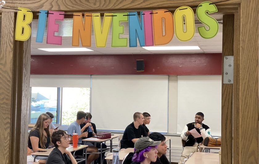 students sitting in spanish class with a colorful bienvenidos sign above the door