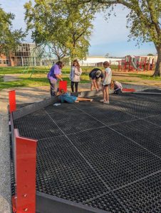 students standing and laying down as they construct a gaga pit