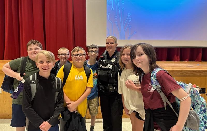 seven students stand with SRO at assembly