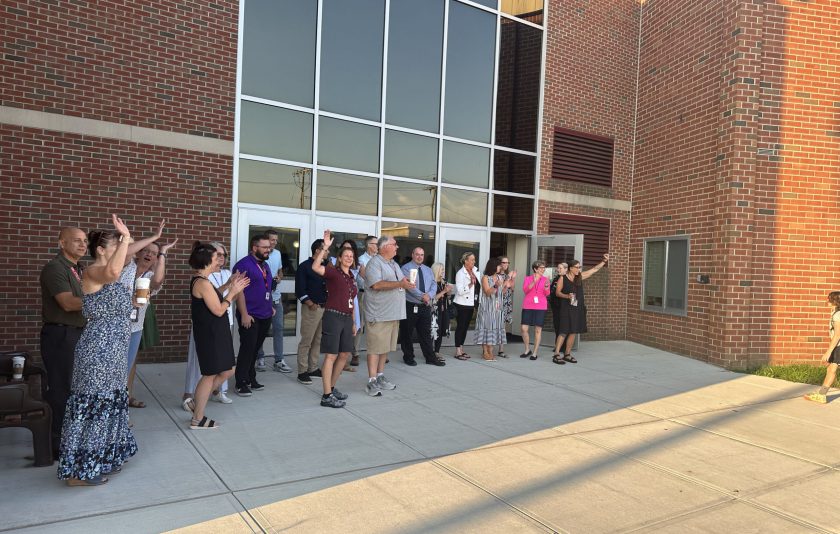 faculty and staff lined up outside the school waiting cheering for new students