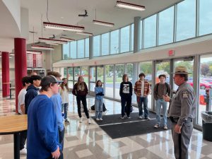 a police officer speaks with students in the lobby of their school