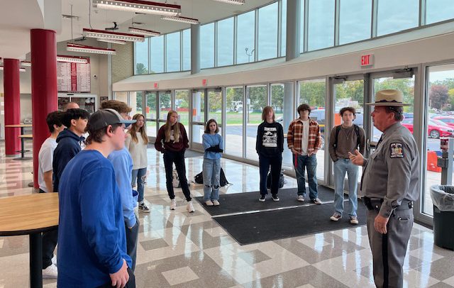 a police officer speaks with students in the lobby of their school