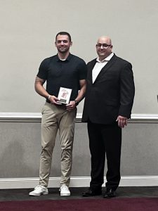 Hall of Fame winner holds award and stands with coach