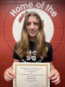 student with long brown hair and black T-shirt holds certificate in front of her with two hands