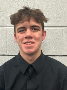 student wearing a black button up shirt smiles for the camera